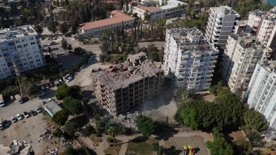 Adana’da yaklaşık 33 yıl önce inşaatına başlanan 11 katlı bina, damına iş makinesi çıkartılarak yıkılıyor
