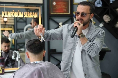 Bir elinde makas diğer elinde mikrofon
