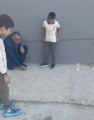 Okul müdürü, öğrencilerle bahçede misket oynadı
