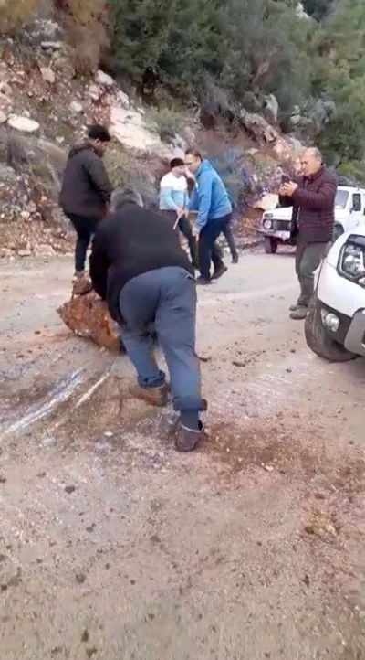 Yola d&uuml;şen kayaları iple araca bağlayıp &ccedil;ektiler
