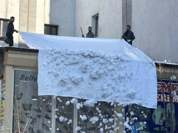 Vatandaşlar çatıdaki kar kütlelerini brandayla indirdi
